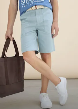 Blaues T-Shirt, hellblaue Shorts, weißer Gürtel und weiße Sneaker bilden ein frisches Sommer-Outfit.