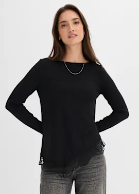 Schwarzes Ripp-Langarmshirt mit elegantem Spitzenbesatz, kombiniert mit lässiger grauer Jeans.