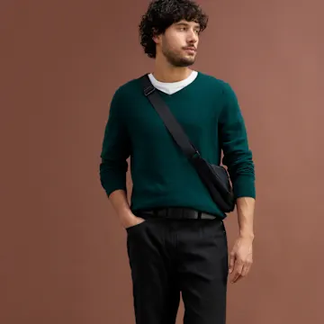 Eleganter dunkelgrüner Pullover über weißem T-Shirt, kombiniert mit schwarzer Hose.