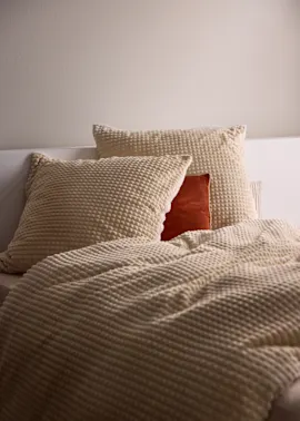 Strukturierte Stoffe in Cremetönen kleiden das Bett weich und gemütlich.