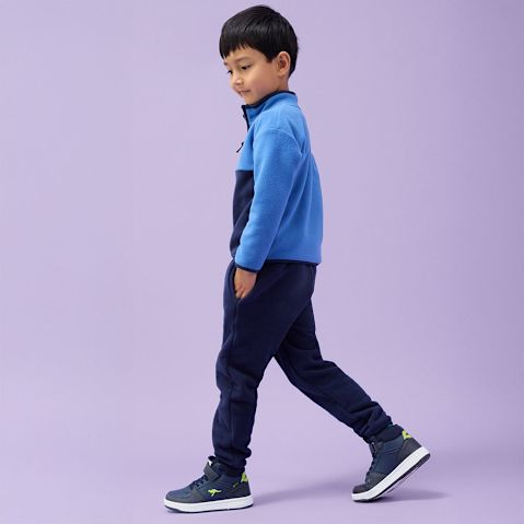 Blaue Fleecejacke, dunkle Jeans und marineblaue Sneakers.