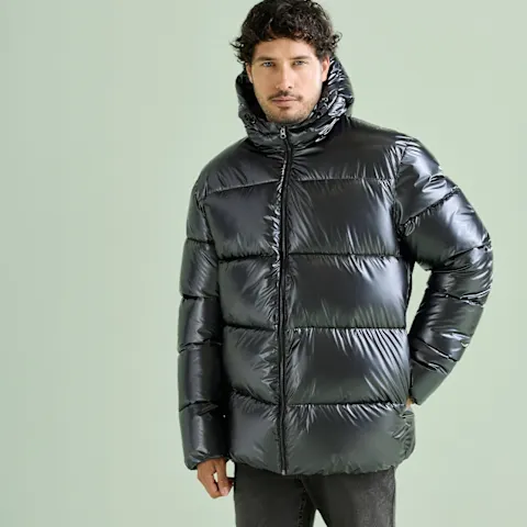 Glänzende, schwarze Daunenjacke mit Kapuze und dunkle Hose, ein lässiger Look.