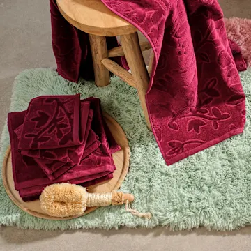 Weiche Badematte und rote Handtücher im Badezimmer.