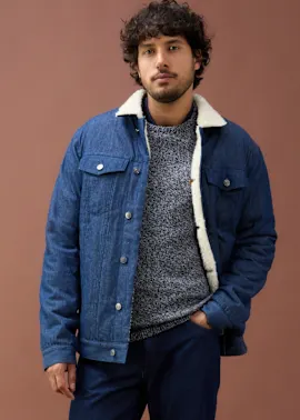 Blaue Jeansjacke mit Fleecefutter, grauer Pullover und dunkle Jeans .