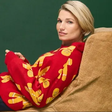 Roter Pullover mit gelben Mustern, dunkler Rock, Strümpfe und braune Stiefel.