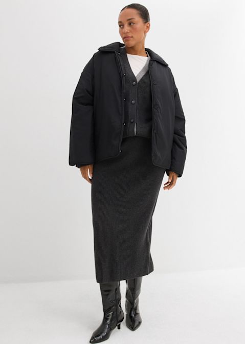 Gesteppte Jacke, langer Rock und Lederstiefel. Schlichtes weißes Oberteil darunter.