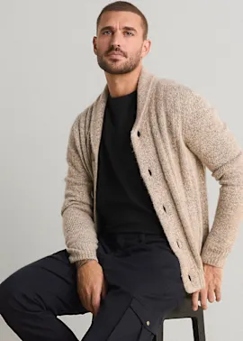 Lässiger Look: beige Strickjacke, schwarzes T-Shirt und dunkelblaue Cargohose.