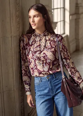 Stilvolle Paisley-Bluse mit Schleife, dazu weite Jeans und passende Ledertasche.