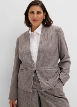Die Frau trägt einen eleganten, gemusterten Blazer, eine weiße Bluse und Hose.