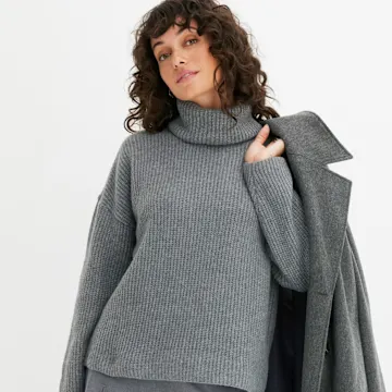 Grauer Rollkragenpullover und passender Mantel.