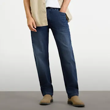 Dunkelblaue Jeans, helles Hemd, weißes T-Shirt und braune Schuhe für lässigen Stil.
