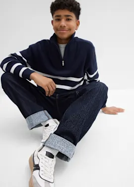 Dunkelblauer Pullover mit weißen Streifen, Jeans und weiße Sneakers.