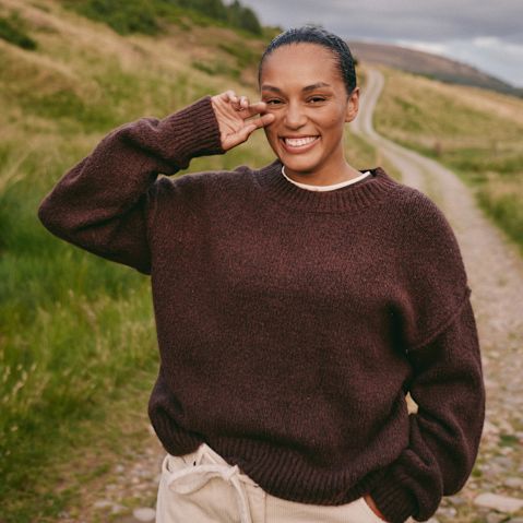 Gemütlicher brauner Pullover mit weißem Kragen, perfekt für einen Spaziergang in der Natur.