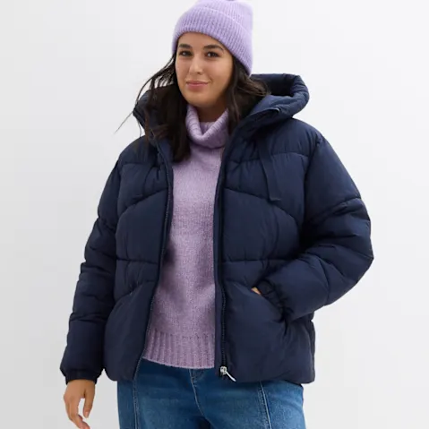 Dunkelblaue Daunenjacke, lila Rollkragen und Strickmütze.