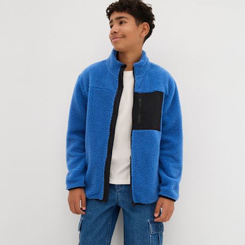 Ein blauer Fleece-Pullover mit schwarzem Einsatz, kombiniert mit Jeans und weißem T-Shirt.