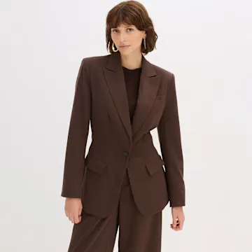 Brauner Blazer und braune Hose. Darunter ein schwarzes Top.
