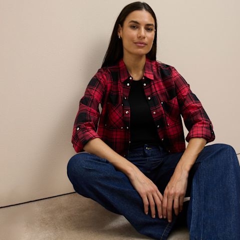 Rot-schwarzes kariertes Hemd über schwarzem Top, kombiniert mit klassischer Jeans.