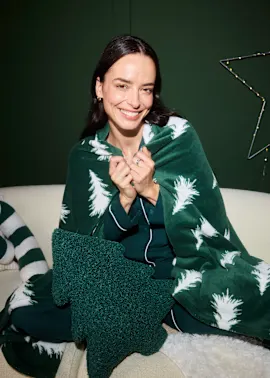 Grüner Pyjama und passende Decke mit Tannenbäumen.