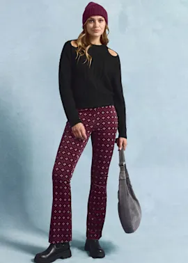 Schwarzer Pullover, gemusterte Leggings in Weinrot, graue Tasche und weinrote Mütze.