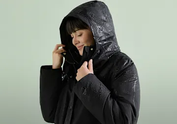 Schwarze, wasserdichte Jacke mit Kapuze. Die Regentropfen perlen ab.