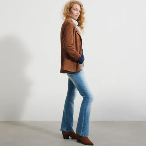 Braune Wildlederjacke, lässige Schlagjeans, weißer Rollkragen und braune Stiefeletten.