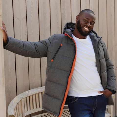 Grauer Winterjacke, weißes Shirt und dunkle Jeans prägen den lässigen Look.