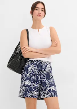 Weiße ärmellose Bluse, dunkelblaue Shorts mit Blumenmuster und schwarze perforierte Tasche.