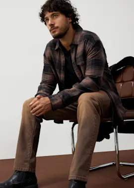 Lässige, braune Jeans,  kariertes Hemd und schwarze Lederstiefel.