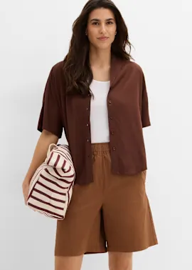 Braunes Overshirt über weißem Top, kombiniert mit bequemen Shorts und gestreifter Tasche.