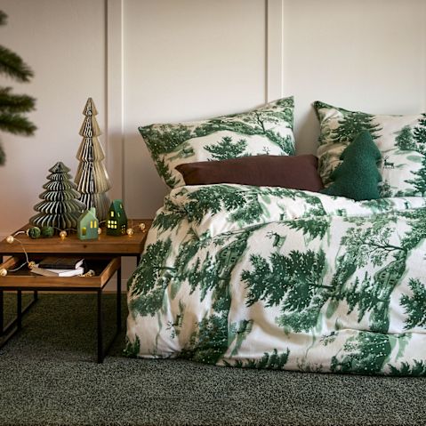 Bettwäsche mit Tannenmuster verleiht dem Schlafzimmer weihnachtliche Atmosphäre.