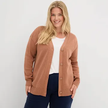 Rostfarbene Strickjacke über weißem Top, kombiniert mit dunkler Jeans.
