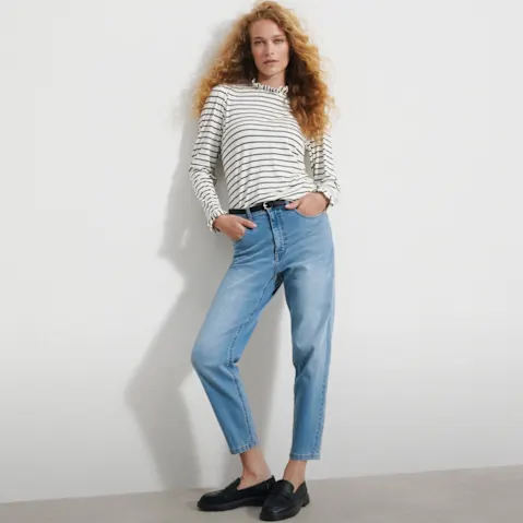 Gestreiftes Langarmshirt, helle High-Waist-Jeans, schwarzer Gürtel und Loafer.