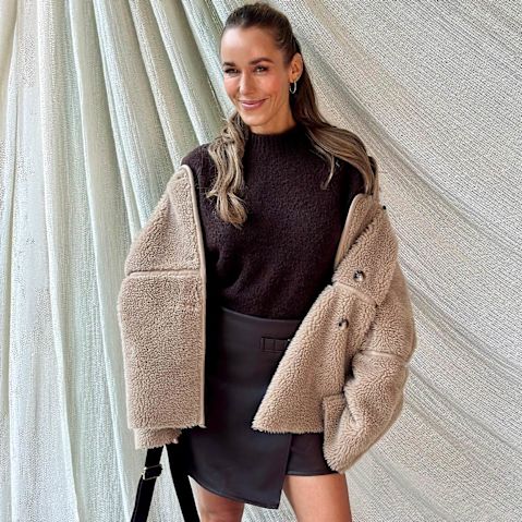 Flauschige Teddyjacke über dunklem Pullover und Rock.
