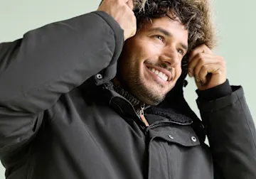 Dunkle Winterjacke mit flauschigem Kapuzenrand schützt vor Kälte.