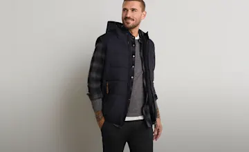 Stylische Steppweste über kariertem Hemd und grauem Pullover für Herren.