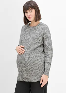 Grauer, melierter Strickpullover für werdende Mütter, kombiniert mit schlichter schwarzer Hose.