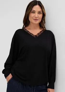 Modernes schwarzes Longsleeve mit zarter Spitze am V-Ausschnitt, dazu dunkle Jeans.