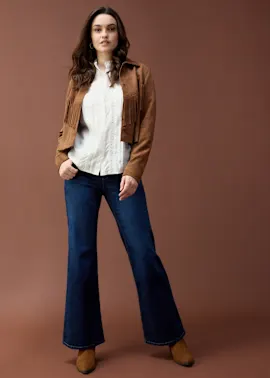 Wildlederjacke über weißer Bluse, kombiniert mit ausgestellter Jeans.