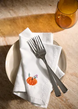 Weiße Stoffserviette mit Kürbis-Stickerei.