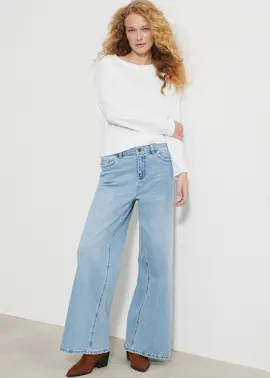 Ein weißes Langarmshirt, eine weite hellblaue Jeans und modische braune Stiefeletten.