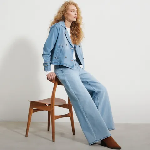 Kurze hellblaue Jeansjacke, weite Hose und weißes Shirt.