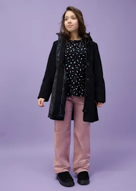 Dunkler Mantel über Oberteil, kombiniert mit rosafarbener Hose und schwarzen Schuhen.