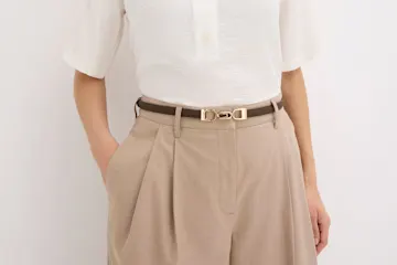 Beige weite Hose, weiße Bluse und eleganter Gürtel mit goldener Schnalle.