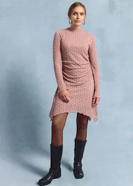 Rosafarbenes Spitzenkleid mit langen Ärmeln, kombiniert mit schwarzen Stiefeln.