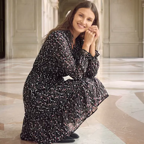 Ein stilvolles, gemustertes Kleid mit langen Ärmeln und eleganten schwarzen Schuhen.