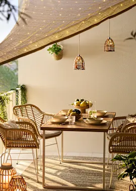 Gemütliche Terrasse mit Rattanstühlen und Holztisch, dekoriert mit Lichterketten und stimmungsvollen Laternen.