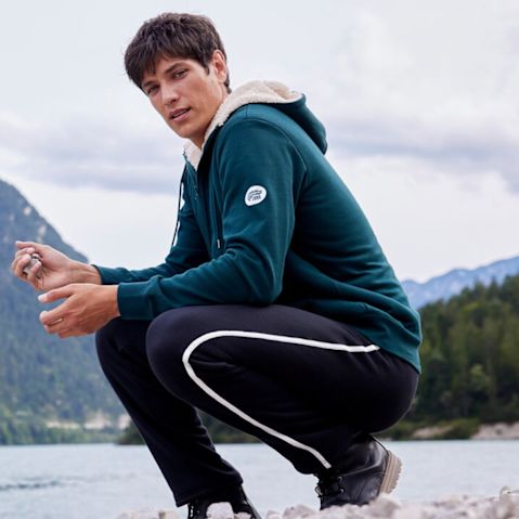 Grüne Sweatjacke und schwarze Jogginghose für aktive Outdoor-Aktivitäten.