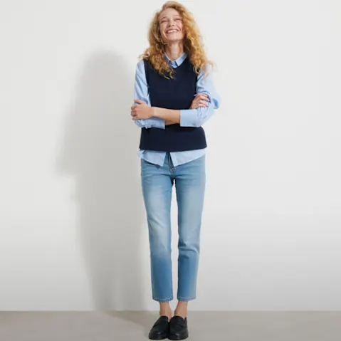 Hellblaues Hemd, dunkelblaue Weste, blaue Jeans und schwarze Loafer.