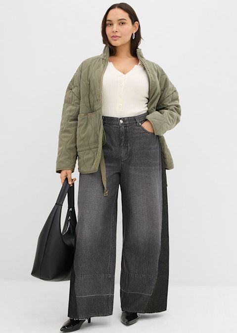 Olivgrüne Steppjacke, weißes Top und weite graue Jeans.