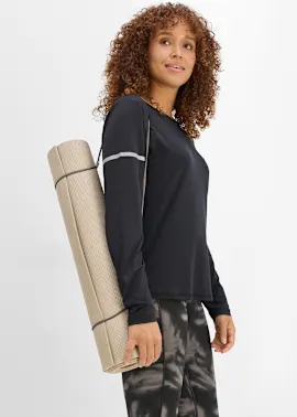 Frau trägt schwarzes Sportshirt mit reflektierenden Details und gemusterte Leggings, hält Yogamatte.